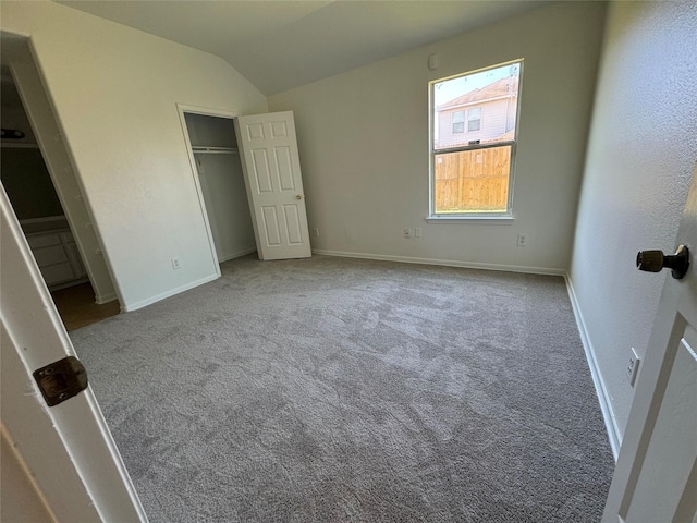 unfurnished bedroom with carpet floors, a closet, and vaulted ceiling