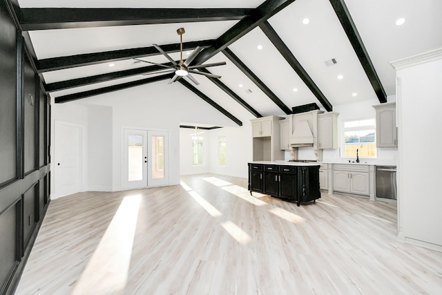 unfurnished living room featuring beam ceiling, ceiling fan, and light wood-type flooring