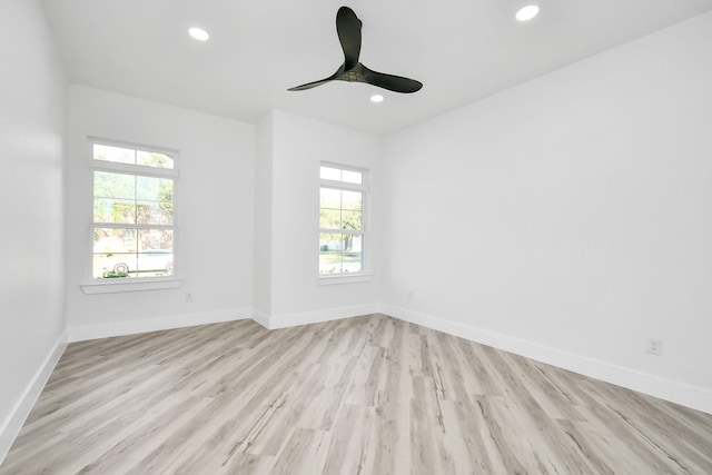 empty room featuring ceiling fan, a wealth of natural light, and light wood-type flooring