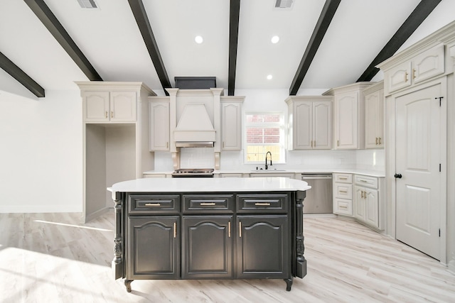 kitchen featuring appliances with stainless steel finishes, tasteful backsplash, sink, a center island, and light wood-type flooring