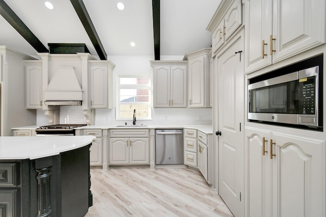 kitchen with tasteful backsplash, sink, beam ceiling, and appliances with stainless steel finishes