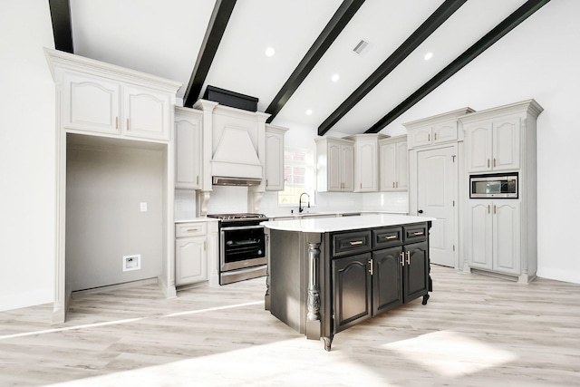 kitchen featuring appliances with stainless steel finishes, a kitchen island, tasteful backsplash, white cabinetry, and beam ceiling