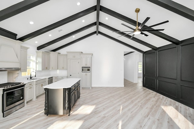 kitchen with sink, stainless steel appliances, a center island, light hardwood / wood-style floors, and white cabinets