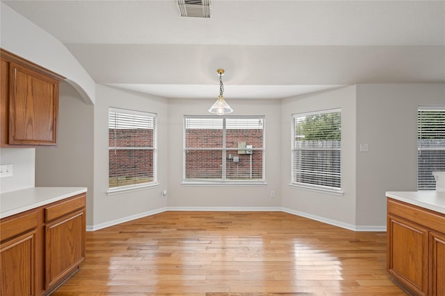 unfurnished dining area featuring arched walkways, visible vents, light wood-style flooring, and baseboards