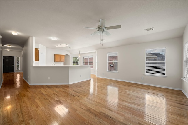 unfurnished living room featuring light wood finished floors, baseboards, visible vents, and a ceiling fan