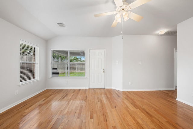 empty room featuring visible vents, baseboards, light wood-style flooring, ceiling fan, and vaulted ceiling