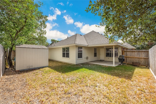 rear view of property featuring an outbuilding, a storage unit, a lawn, a patio area, and a fenced backyard