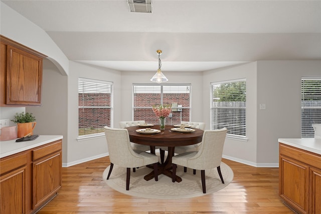 dining area with arched walkways, baseboards, visible vents, and light wood finished floors