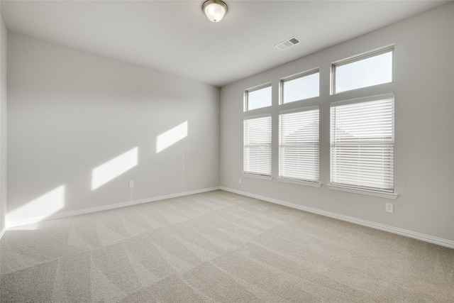 unfurnished room featuring plenty of natural light and light carpet