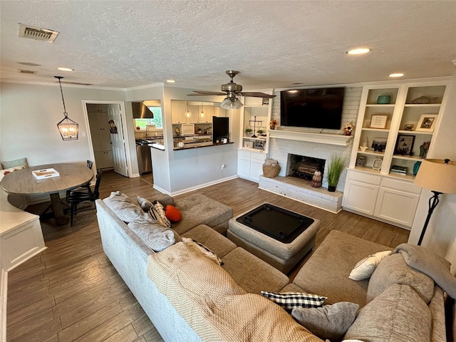 living room featuring dark hardwood / wood-style flooring, crown molding, a fireplace, and a textured ceiling