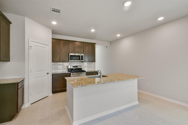 1312 Cypress Ln, Dayton, TX 77535 - kitchen with stainless steel appliances, decorative backsplash, light stone counters, an island with sink, and recessed lighting