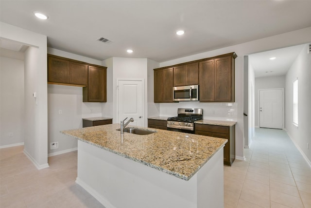 1312 Cypress Ln, Dayton, TX 77535 - kitchen with appliances with stainless steel finishes, light stone counters, light tile patterned floors, a center island with sink, and recessed lighting