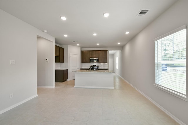1312 Cypress Ln, Dayton, TX 77535 - kitchen featuring stainless steel appliances, recessed lighting, dark brown cabinetry, an island with sink, and light tile patterned flooring