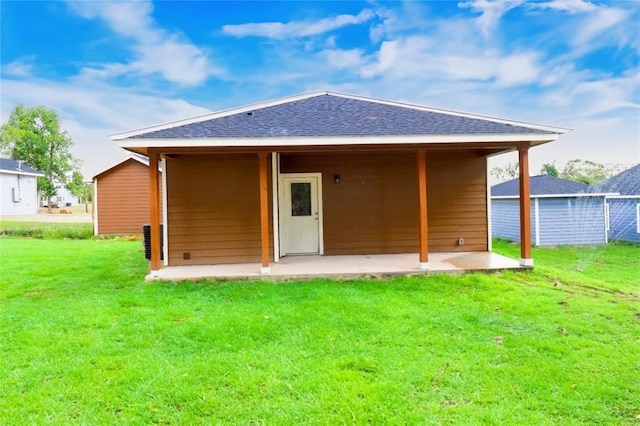 back of property with a yard, a patio, and roof with shingles