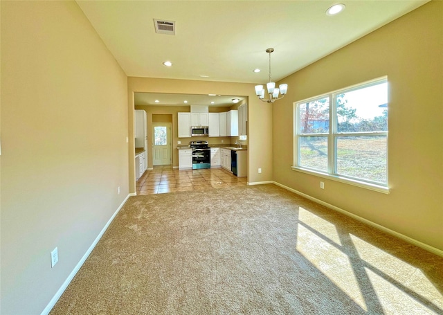 unfurnished living room with an inviting chandelier, a healthy amount of sunlight, sink, and light carpet