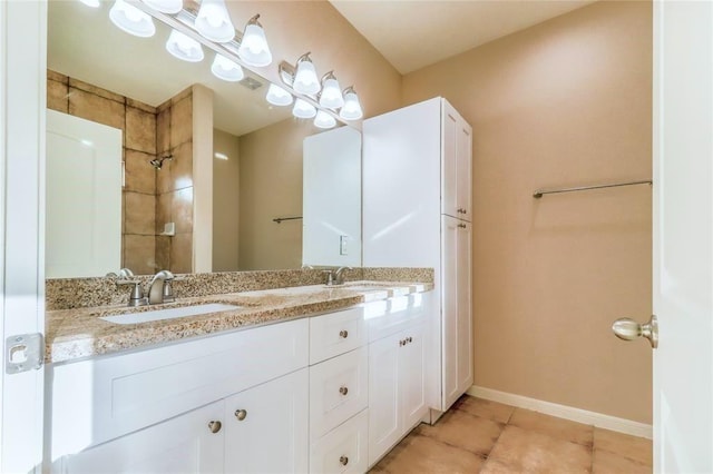 bathroom featuring double vanity, a sink, baseboards, and tile patterned floors