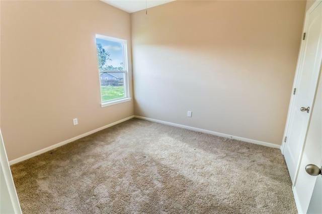 spare room featuring light carpet and baseboards