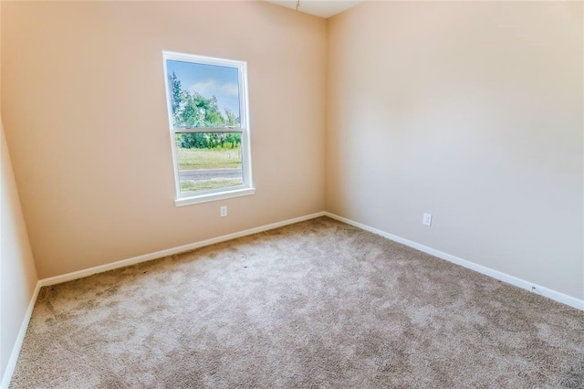 spare room featuring light carpet and baseboards