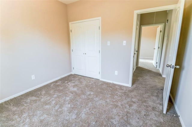 unfurnished bedroom featuring attic access, baseboards, a closet, and light colored carpet