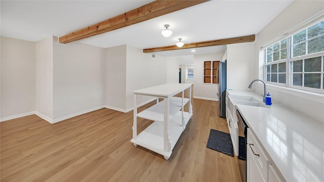 kitchen with sink, white cabinets, beam ceiling, stainless steel appliances, and light wood-type flooring