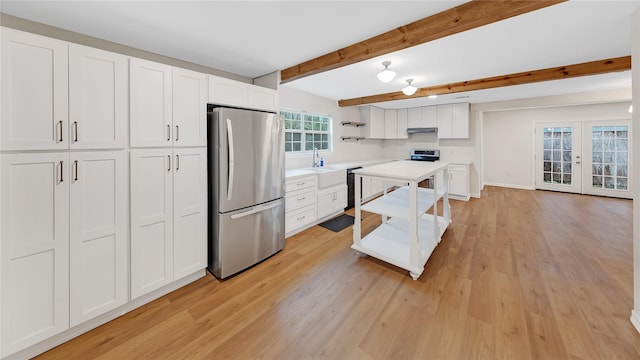 kitchen featuring stainless steel fridge, white cabinetry, beam ceiling, light hardwood / wood-style floors, and french doors