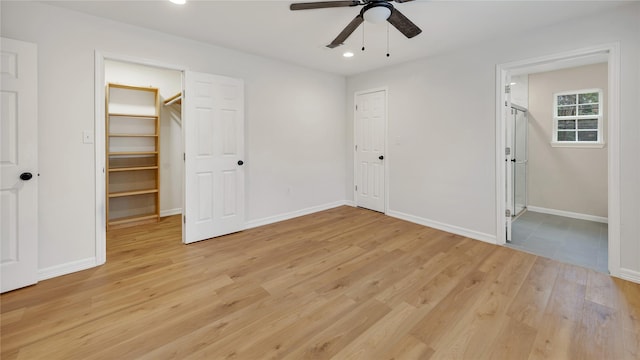 unfurnished bedroom with light hardwood / wood-style flooring, a walk in closet, a closet, and ceiling fan