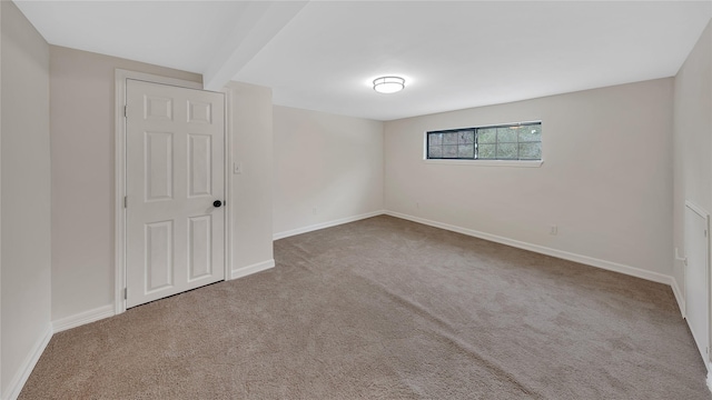 carpeted spare room featuring beamed ceiling