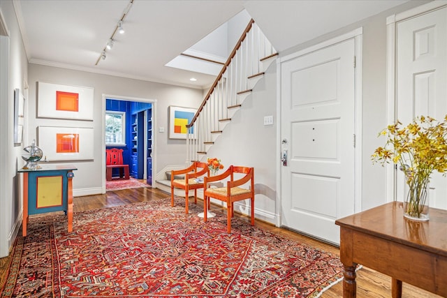 entrance foyer with ornamental molding, wood-type flooring, and rail lighting