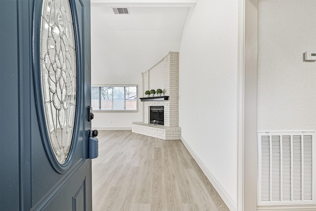 entryway with a brick fireplace and light hardwood / wood-style floors