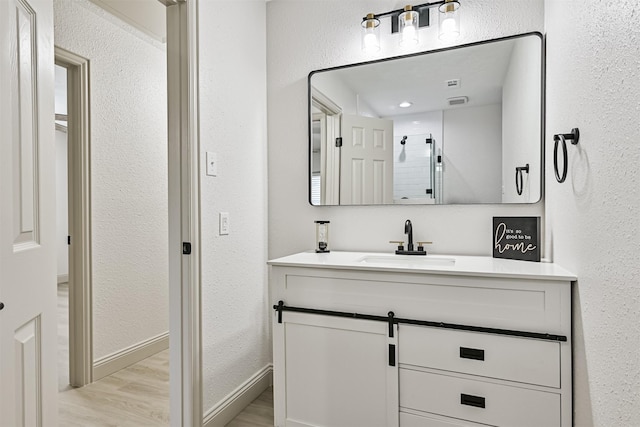 bathroom with hardwood / wood-style flooring, vanity, and a shower