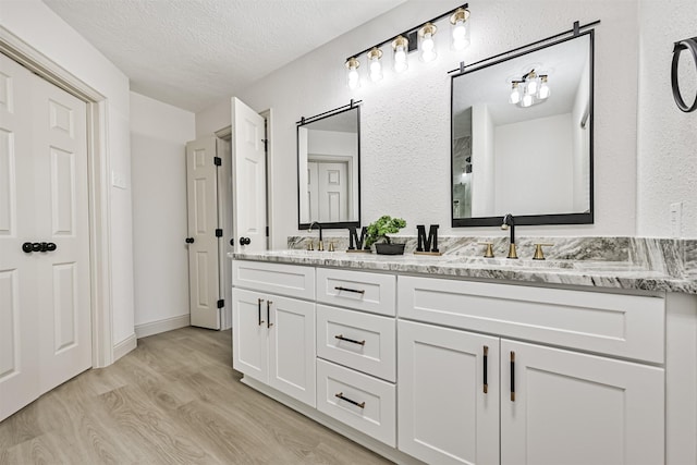 bathroom featuring wood-type flooring, vanity, and a textured ceiling