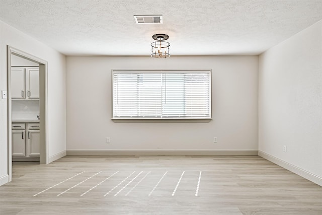 unfurnished room featuring light hardwood / wood-style flooring and a textured ceiling