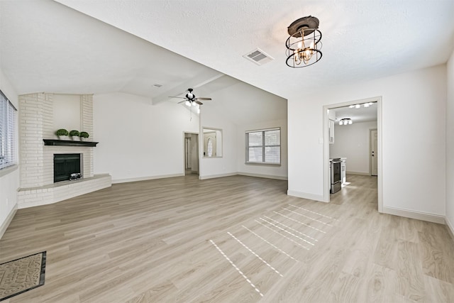 unfurnished living room with lofted ceiling, a textured ceiling, a brick fireplace, ceiling fan with notable chandelier, and light wood-type flooring