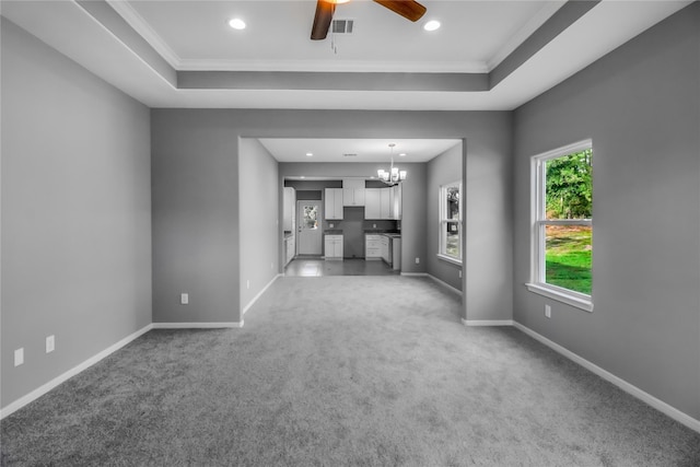 unfurnished living room featuring ornamental molding, a tray ceiling, ceiling fan with notable chandelier, and carpet