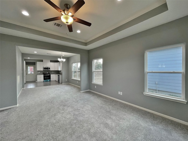 unfurnished living room featuring light carpet, ceiling fan with notable chandelier, and a tray ceiling