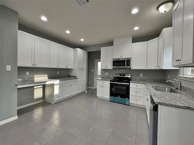 kitchen with recessed lighting, appliances with stainless steel finishes, white cabinetry, a sink, and light stone countertops