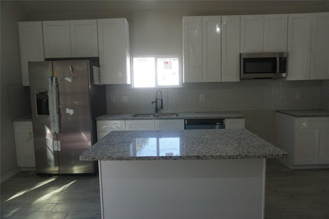 kitchen featuring light stone counters, backsplash, stainless steel appliances, and white cabinets