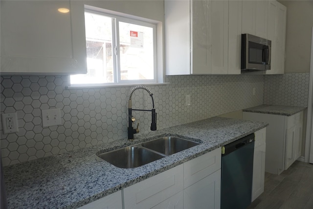 kitchen with sink, light stone counters, backsplash, dishwashing machine, and white cabinets