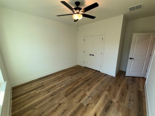 unfurnished bedroom featuring ceiling fan, dark hardwood / wood-style flooring, and a closet