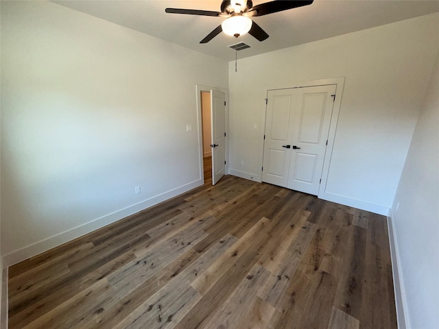 unfurnished bedroom with ceiling fan, dark hardwood / wood-style floors, and a closet