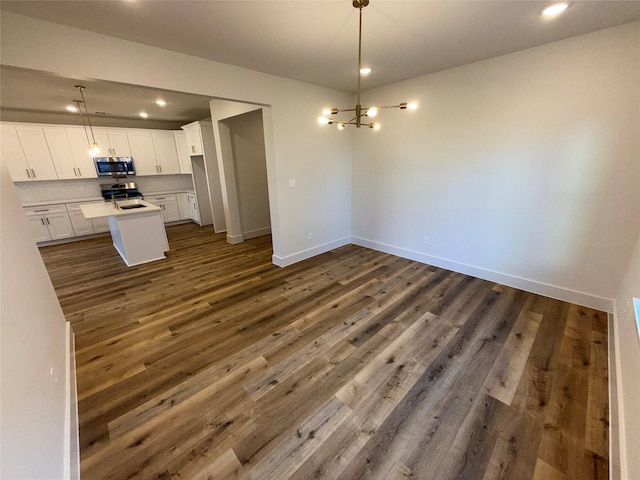 kitchen with dark wood-type flooring, a center island, pendant lighting, stainless steel appliances, and white cabinets