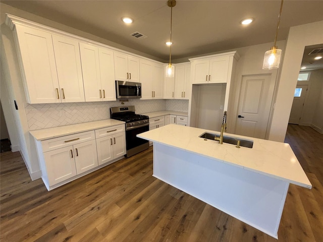 kitchen featuring sink, appliances with stainless steel finishes, white cabinetry, hanging light fixtures, and light stone counters