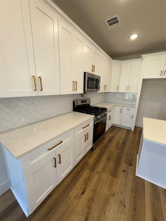 kitchen with stainless steel appliances, light stone countertops, dark hardwood / wood-style floors, and white cabinets