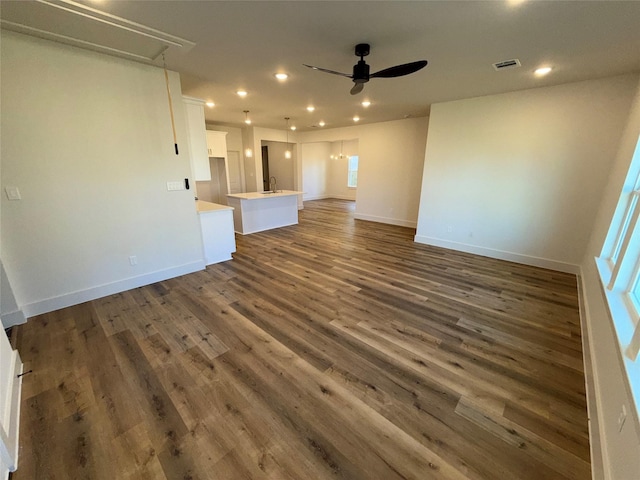 unfurnished living room featuring dark wood-type flooring, sink, and ceiling fan