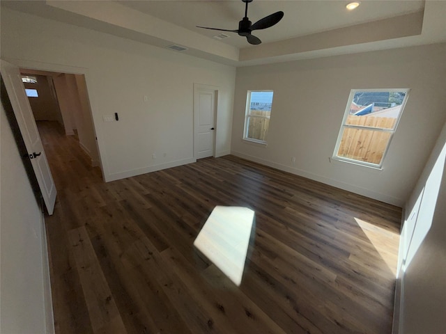 unfurnished bedroom with dark wood-type flooring, ceiling fan, and a tray ceiling