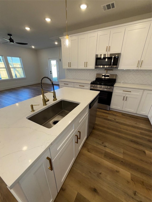 kitchen featuring sink, white cabinetry, hanging light fixtures, stainless steel appliances, and light stone countertops