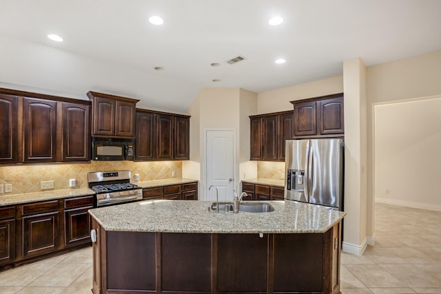 kitchen with dark brown cabinetry, stainless steel appliances, and a center island with sink