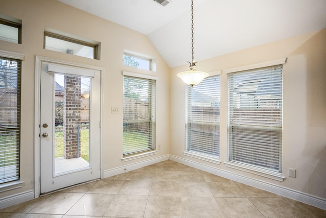 doorway featuring a healthy amount of sunlight, lofted ceiling, and light tile patterned floors