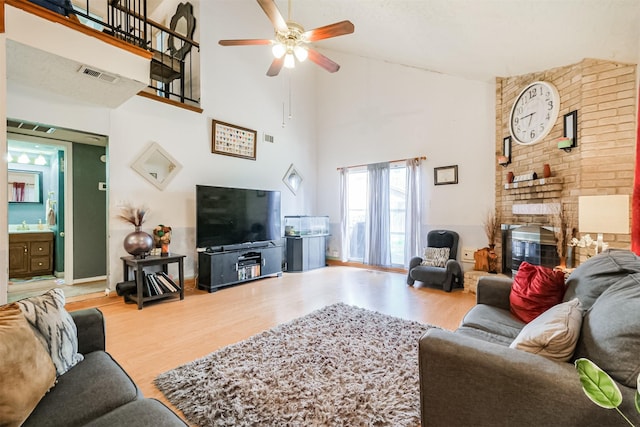 living room featuring hardwood / wood-style flooring, a fireplace, high vaulted ceiling, and ceiling fan