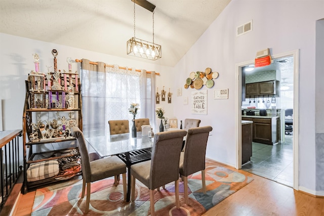 dining room featuring hardwood / wood-style flooring, high vaulted ceiling, and a chandelier